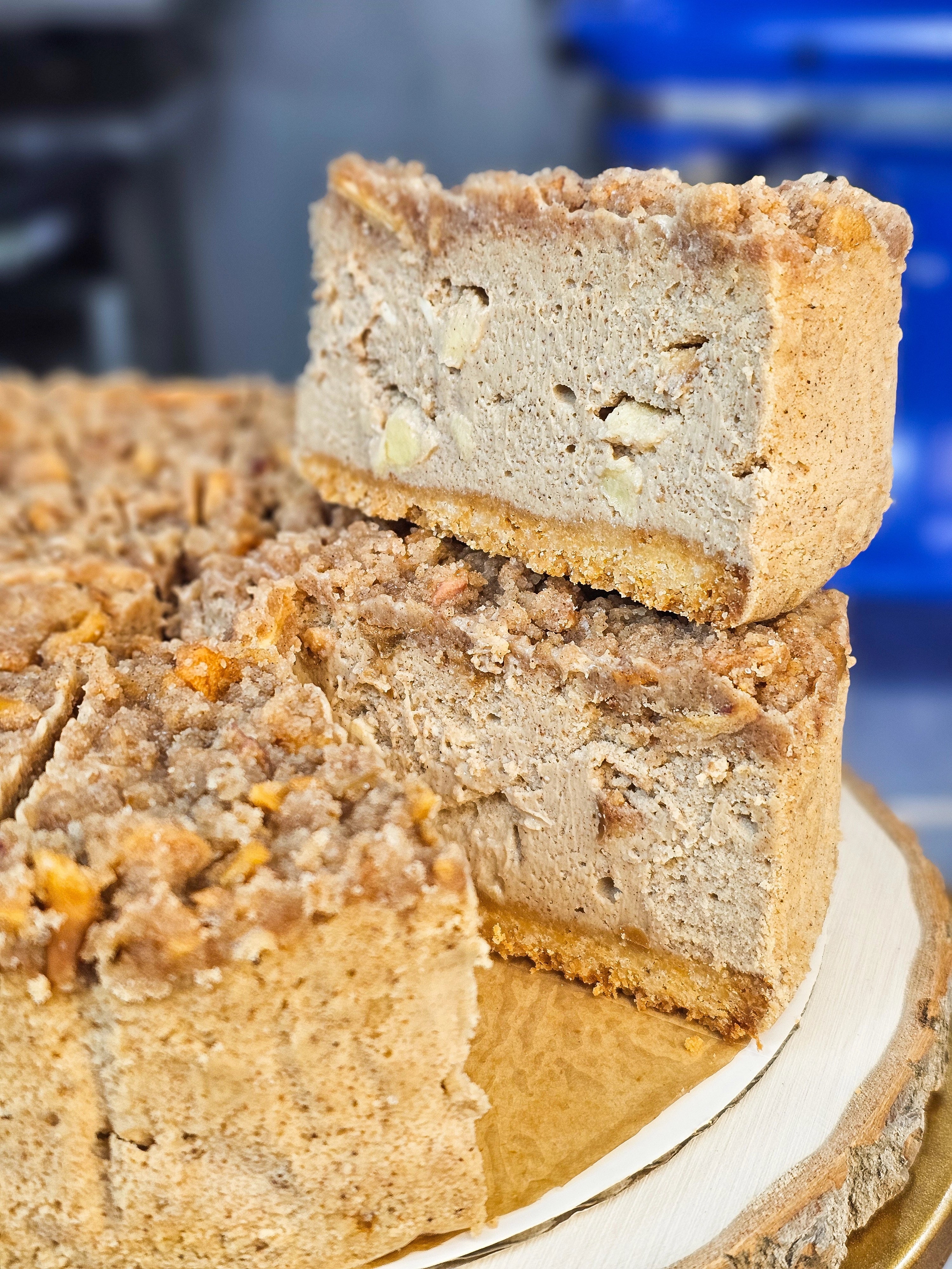Thick slice of Protein Snack Shop’s Harvest Apple Cheesecake, showing a dense, creamy texture with real apple pieces and a cinnamon crumble topping.