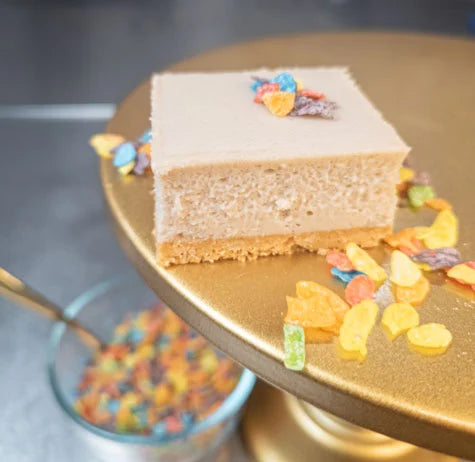 Tutti Frutti cheesecake bar on a gold dessert stand with colorful cereal topping pieces.