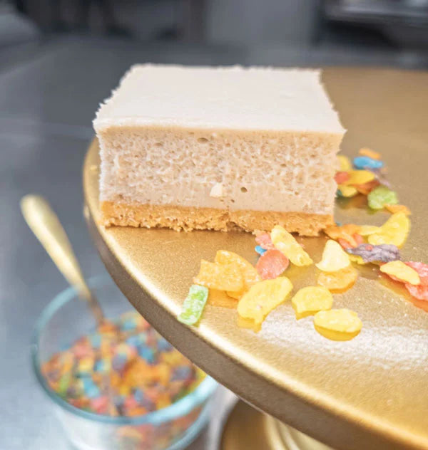 Tutti Frutti cheesecake bar on a gold dessert stand with colorful cereal topping pieces.
